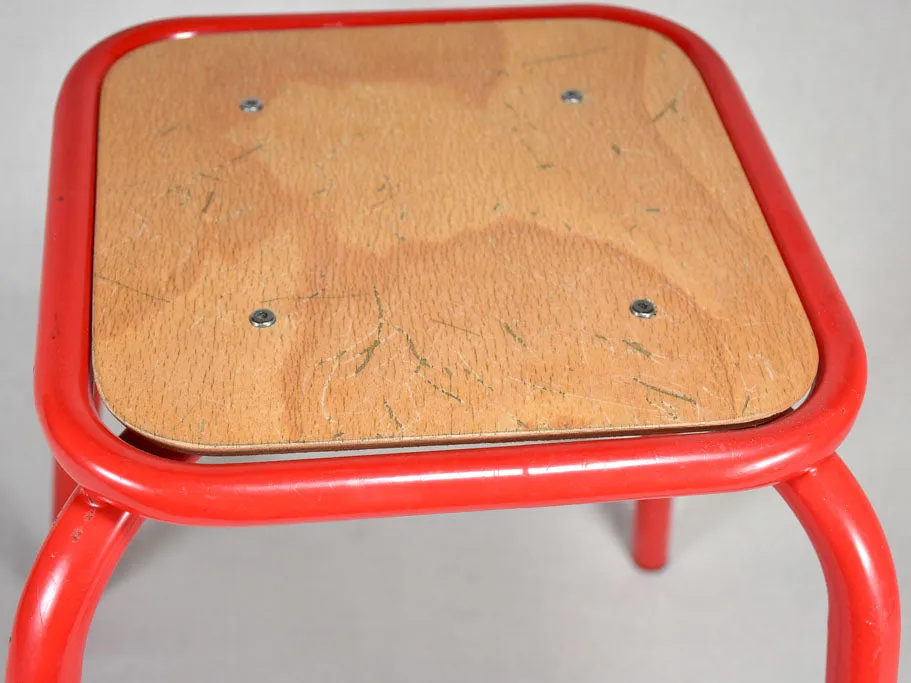 Set of ten red vintage stools from a school